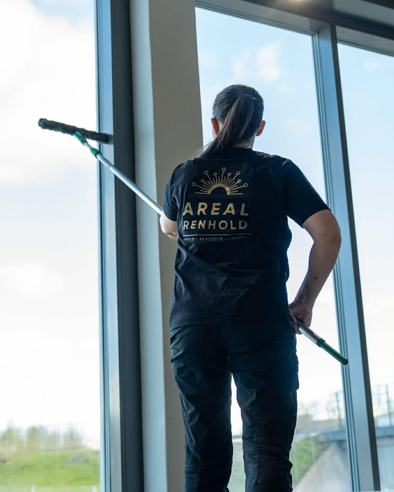 Medarbeider fra Areal Renhold vasker store vindusflater