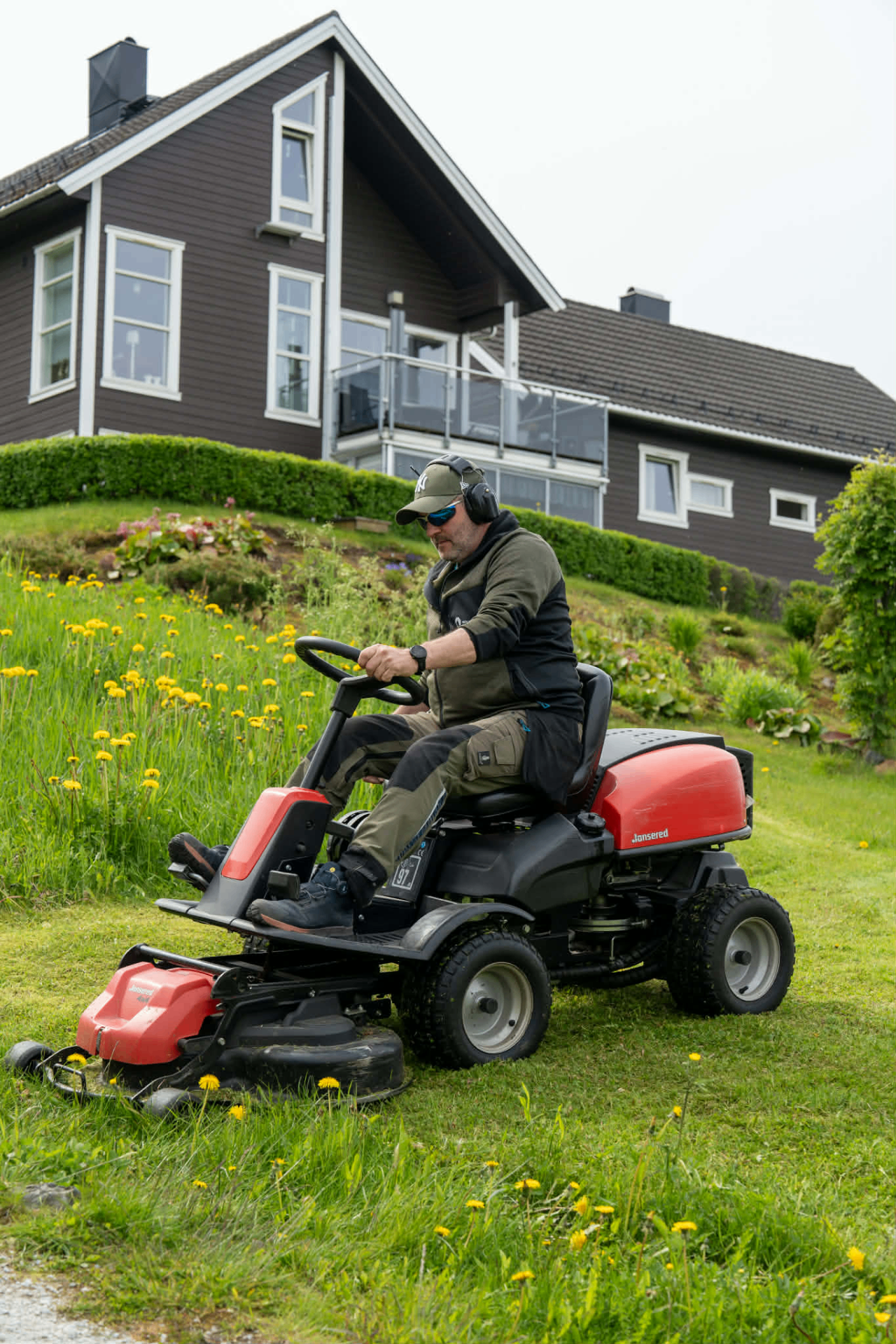 Vaktmester fra Boligservice Helgeland klipper plen ved et bolighus